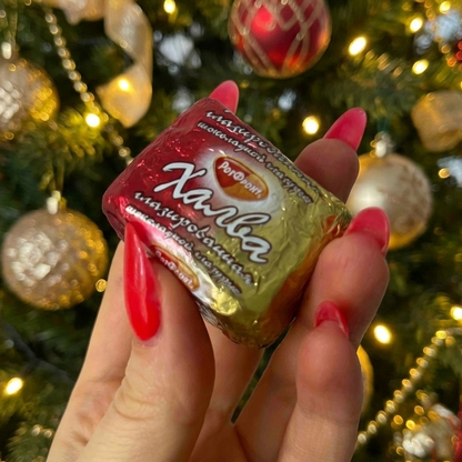 Hand holding a Halva Candies in Chocolate, Rot Front with a Christmas tree in the background
